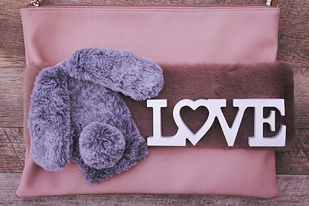 pink, purple and brown zippered bag on top of brown wooden surface thumbnail