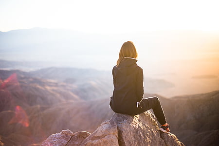 woman sitting on cliff during daytime thumbnail