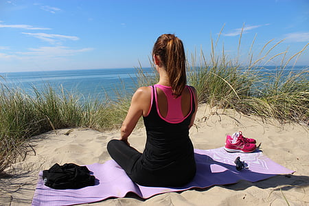 woman sitting on purple yoga mat in front of body of water thumbnail