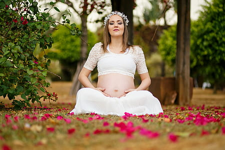 woman wearing white crop top and white skirt sitting on green grass with petals thumbnail