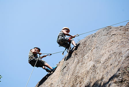 two men climbing on cliff under blue sky thumbnail