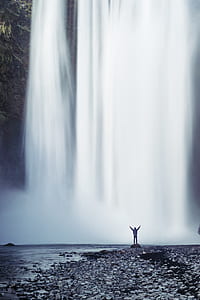person stand in front of waterfalls thumbnail