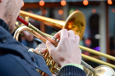 man playing brass-colored trumpet outdoor during daytime thumbnail