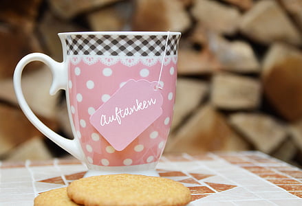 white, pink, and black ceramic mug on table with cookies thumbnail