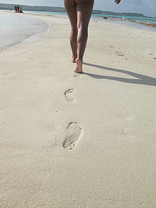 person walking on sand beside boy of water during daytime thumbnail