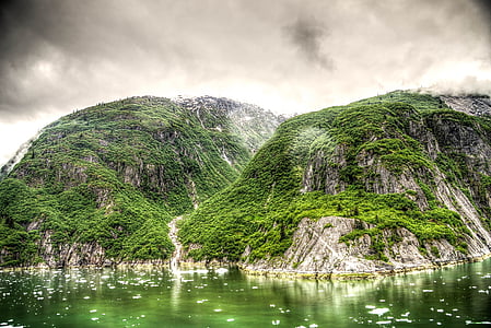 mountain covered with green plants under cloudy sky during daytime thumbnail