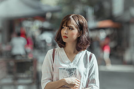 selective focus photography of woman holding book thumbnail