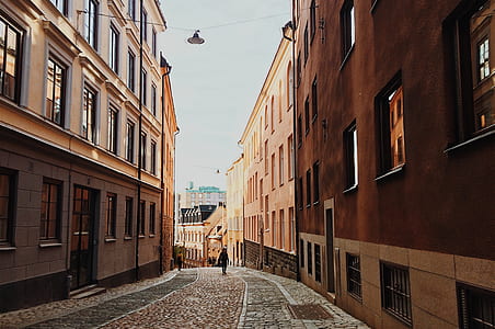 person walking in a road between buildings thumbnail