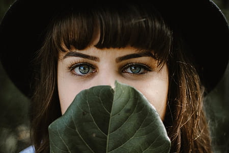 closeup photo of woman's face covered with green leaf thumbnail