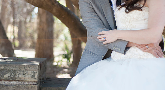 man in gray shawl lapel hugging woman in white floral off-shoulder gown thumbnail