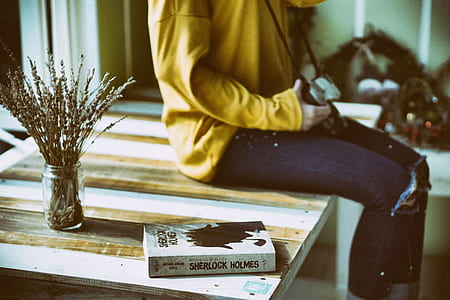 person sitting on table near Sherlock Holmes book thumbnail