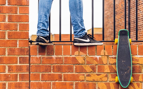 person wear black Nike sneakers standing on concrete brick wall thumbnail