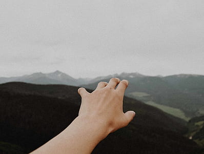 left human hand raising nearby mountains thumbnail