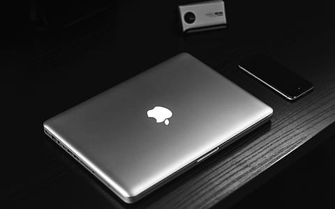 silver MacBook on table beside smartphone thumbnail