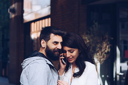 man in gray jacket beside woman with taking call with smartphone thumbnail