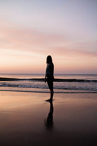 silhouette of woman standing on shore thumbnail