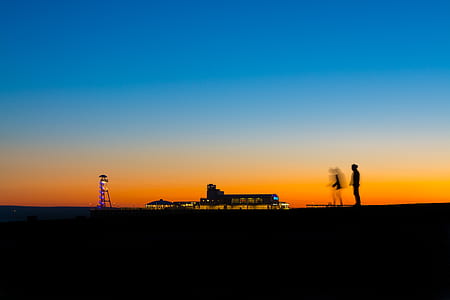 silhouette of persons standing near building during golden hour thumbnail