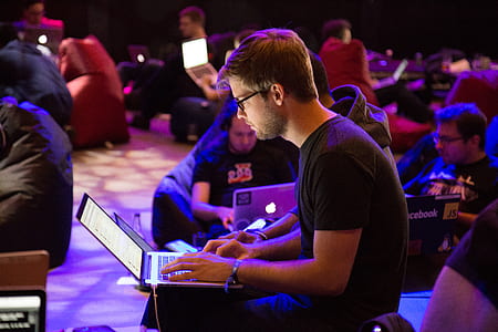 man in black crew-neck t-shirt and black pants using laptop during nighttime thumbnail