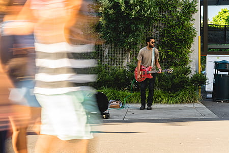 man holding red electric guitar standing on gray pavement during daytime thumbnail