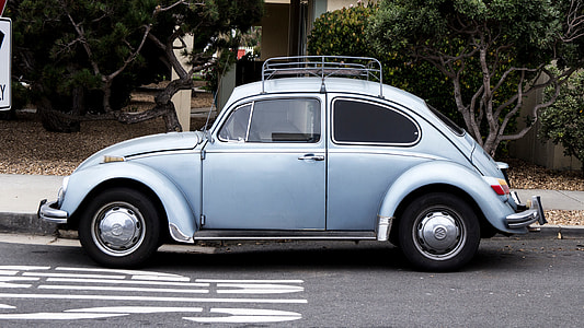 grey Volkswagen Beetle on road side beside trees at daytime thumbnail