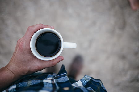 person holding black coffee filled white ceramic mug thumbnail