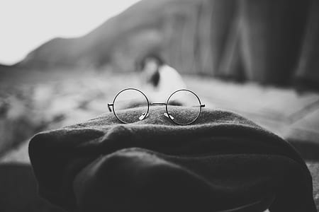 grayscale photo of eyeglasses on brown apparel thumbnail