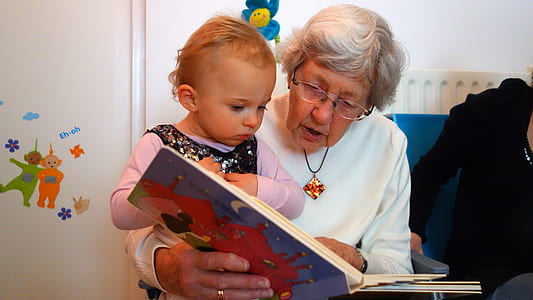 woman wearing white sweater holding book with girl in purple long-sleeved shirt thumbnail