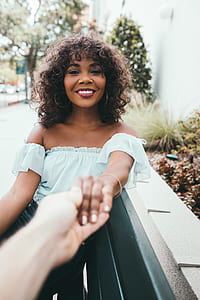woman wearing white off-shoulder shirt sitting on bench while holding persons hand thumbnail