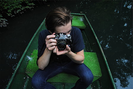 man sitting on boat holding camera thumbnail