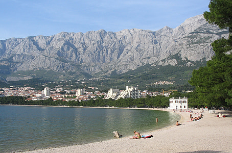 people at beach with mountain and city in background thumbnail