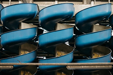 three blue metal spiral slides near white wall thumbnail