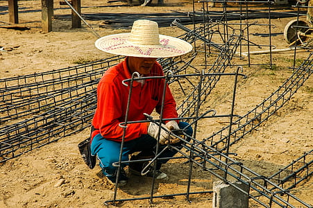 man squatting on ground while holding black metal frames during daytime thumbnail