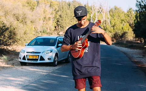 man holding guitar near car thumbnail