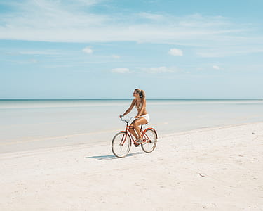 woman in white swimming suit riding bicycle on shore thumbnail