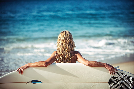 Woman on summer beach with surfboard thumbnail