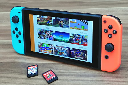 Nintendo Switch turned on on brown surface near two game cartridges thumbnail