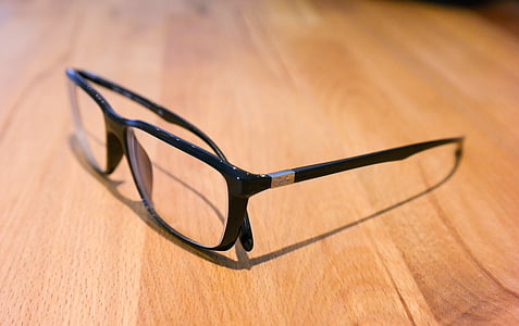 black framed eyeglasses on brown wooden table thumbnail