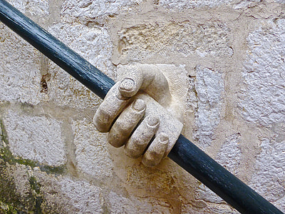 concrete hand holding black metal rod thumbnail