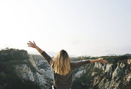 Woman With Blonde Hair at the Top of the Mountain Raising Her Hands thumbnail