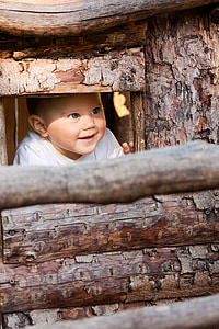 baby in whit v-neck shirt peeping through brown wooden windpw thumbnail