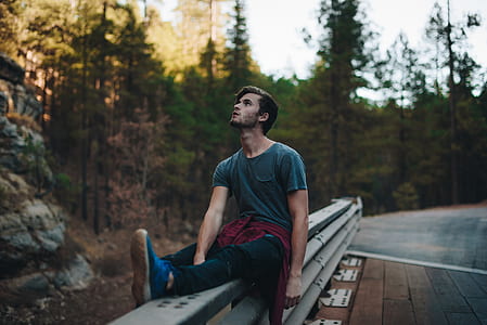 selective focus photography of man sitting on gray metal railings thumbnail