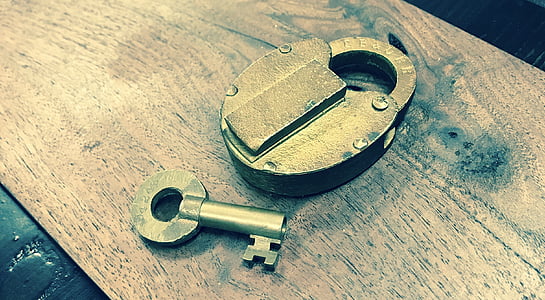 gray padlock beside key on brown wooden board thumbnail