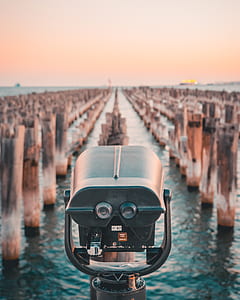 grey and black coin operated binocular facing sea with wooden stomps at daytime thumbnail