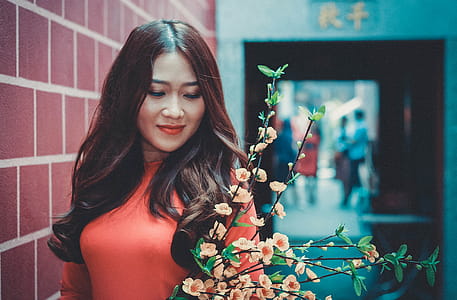 Woman Wearing Red Long-sleeved Shirt in Front of Flower thumbnail
