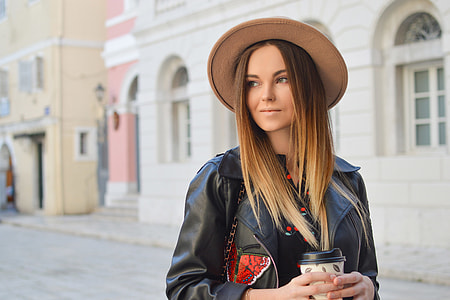 selective focus photography of woman holding disposable coffee cup thumbnail