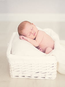 sleeping baby lying on white pillow on white wicker basket thumbnail