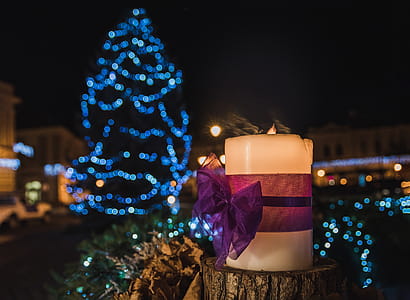 White Pillar Candle on the Log in a Distance of Blue Led Light Christmas Tree thumbnail