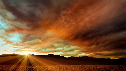 sun rays from silhouette of mountain during cloudy day thumbnail