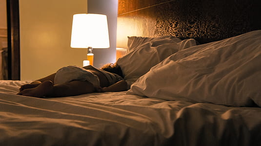 baby lying on bed beside turned on table lamp thumbnail