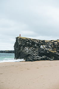 person standing on rocks facing body of water thumbnail